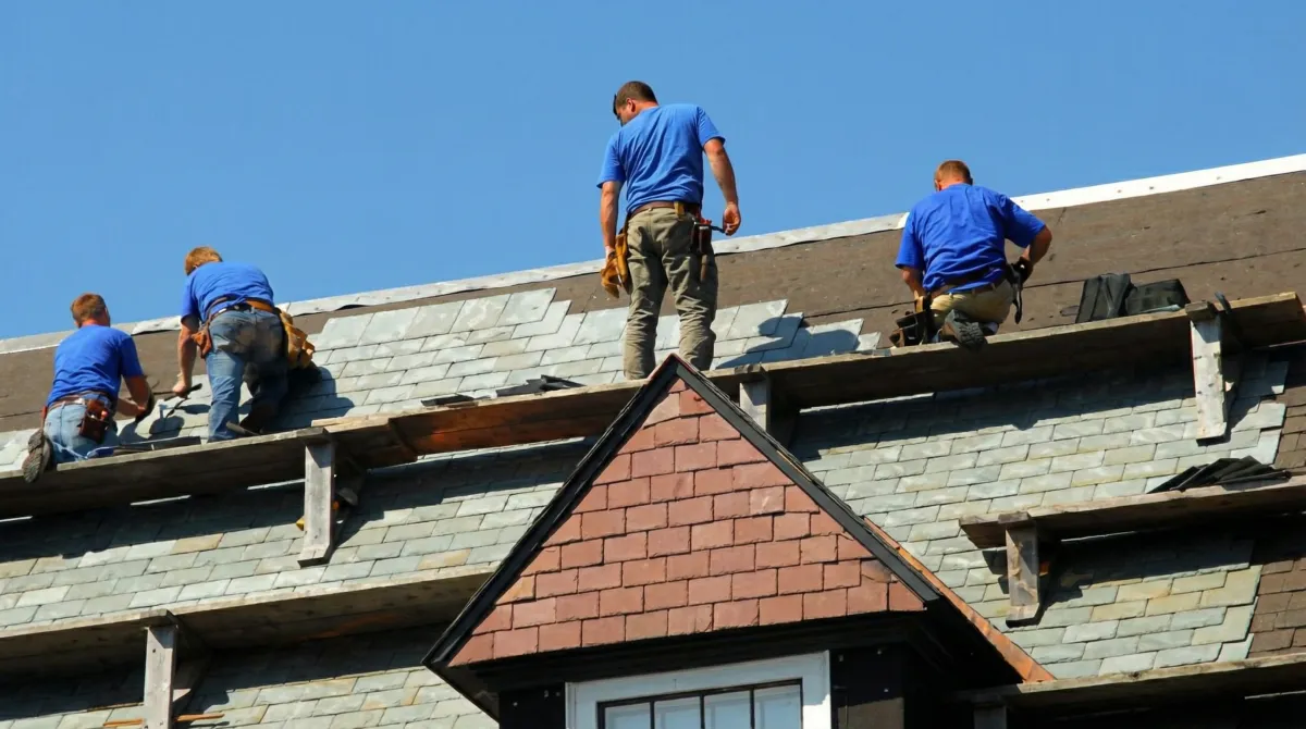 Roof replacement in progress with a team of professional contractors installing new shingles on a residential home in Columbia, MO